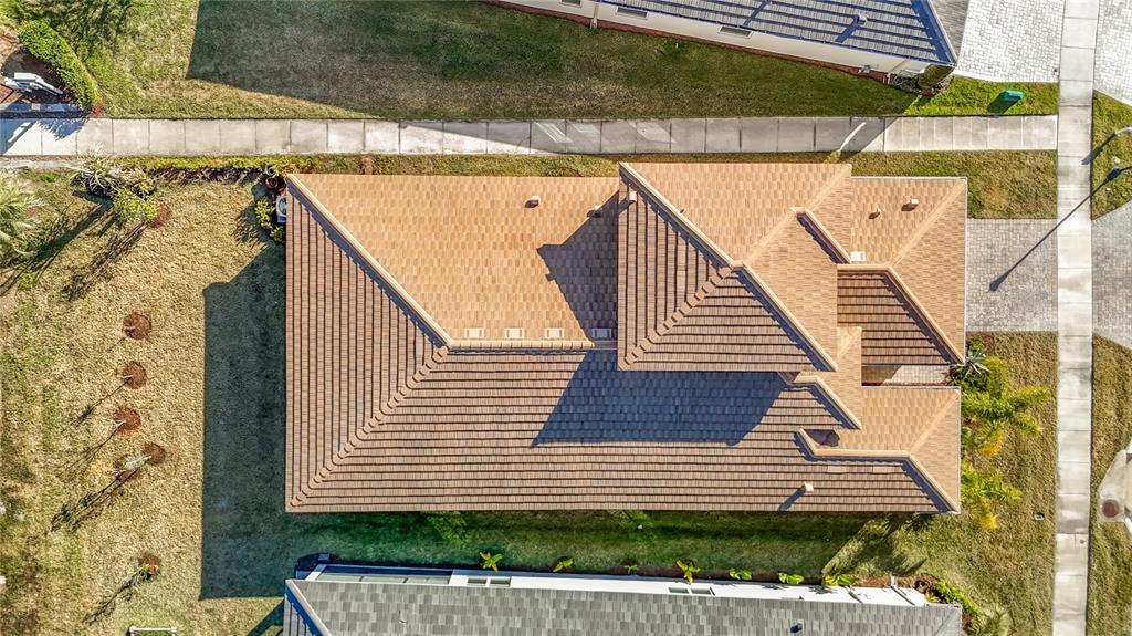 An aerial view shows the brown tiled roof of a house surrounded by green lawns — 32676 TREE OF LIFE AVENUE, WESLEY CHAPEL, FL