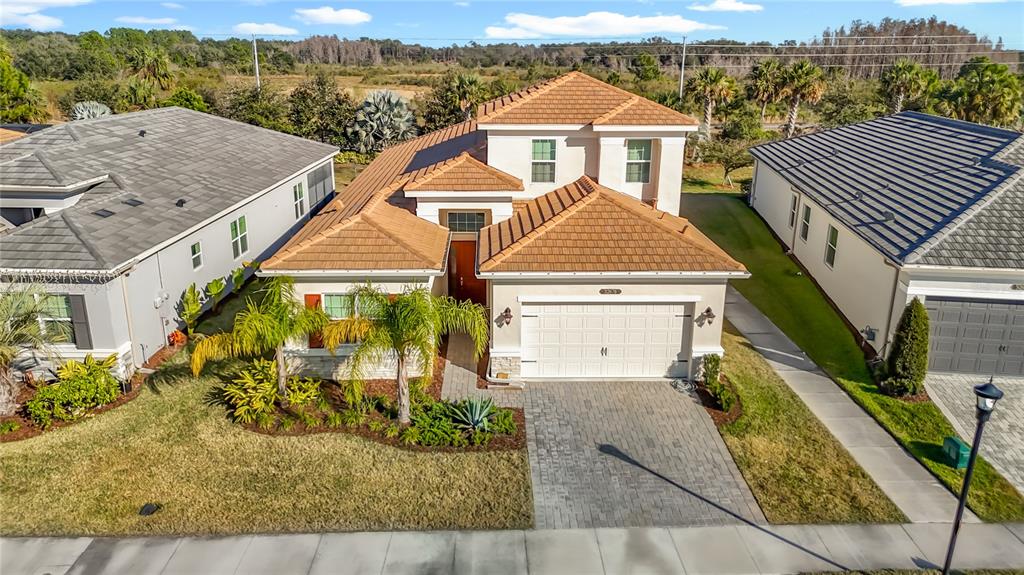 An aerial view of a two-story suburban house with a tiled roof and paved driveway — 32676 TREE OF LIFE AVENUE, WESLEY CHAPEL, FL
