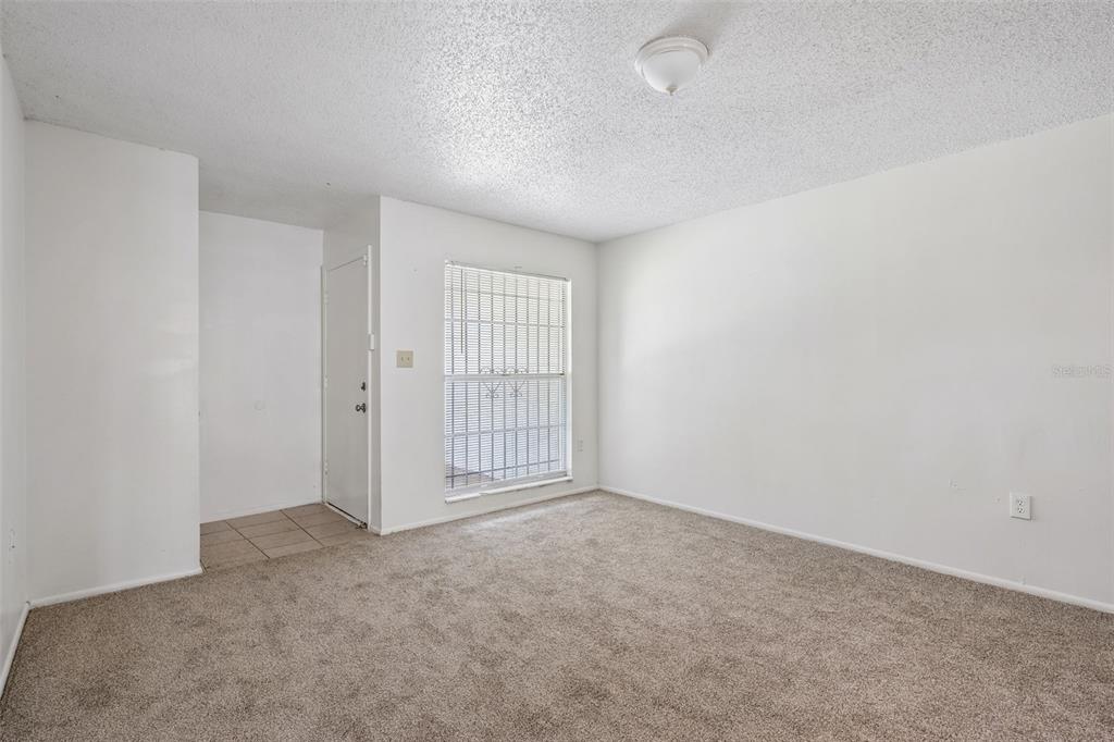 An empty room with beige carpet, white walls, a ceiling light, and a window with bars — 2869 WILLOW RUN, ORLANDO, FL