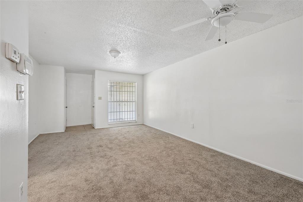 An empty room features beige carpet, white walls, a ceiling fan, and a barred window — 2869 WILLOW RUN, ORLANDO, FL