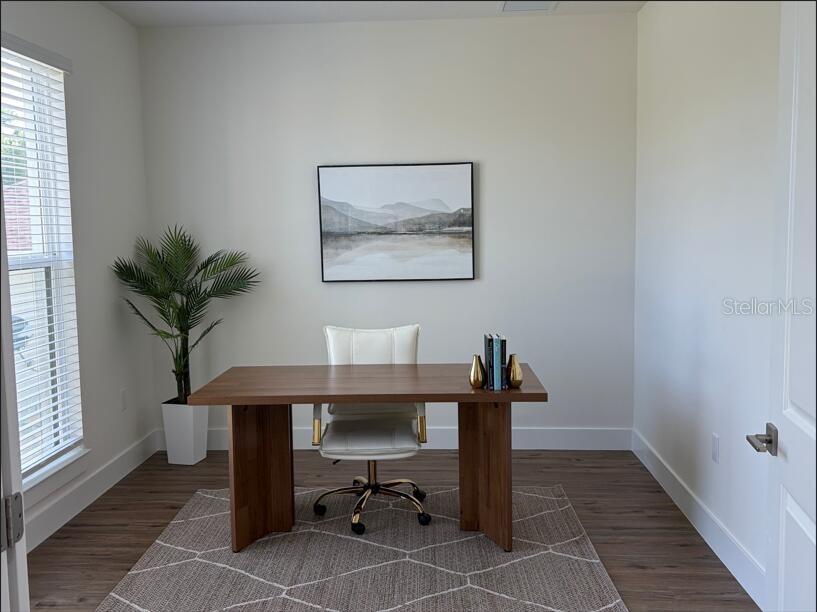 A home office features a wooden desk, a white chair, a rug, and wall art — 14150 OSTROM AVENUE, PORT CHARLOTTE, FL