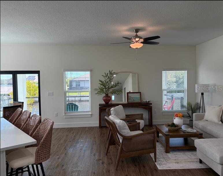 A living and dining area features wood-look flooring, a ceiling fan, and large windows — 14150 OSTROM AVENUE, PORT CHARLOTTE, FL