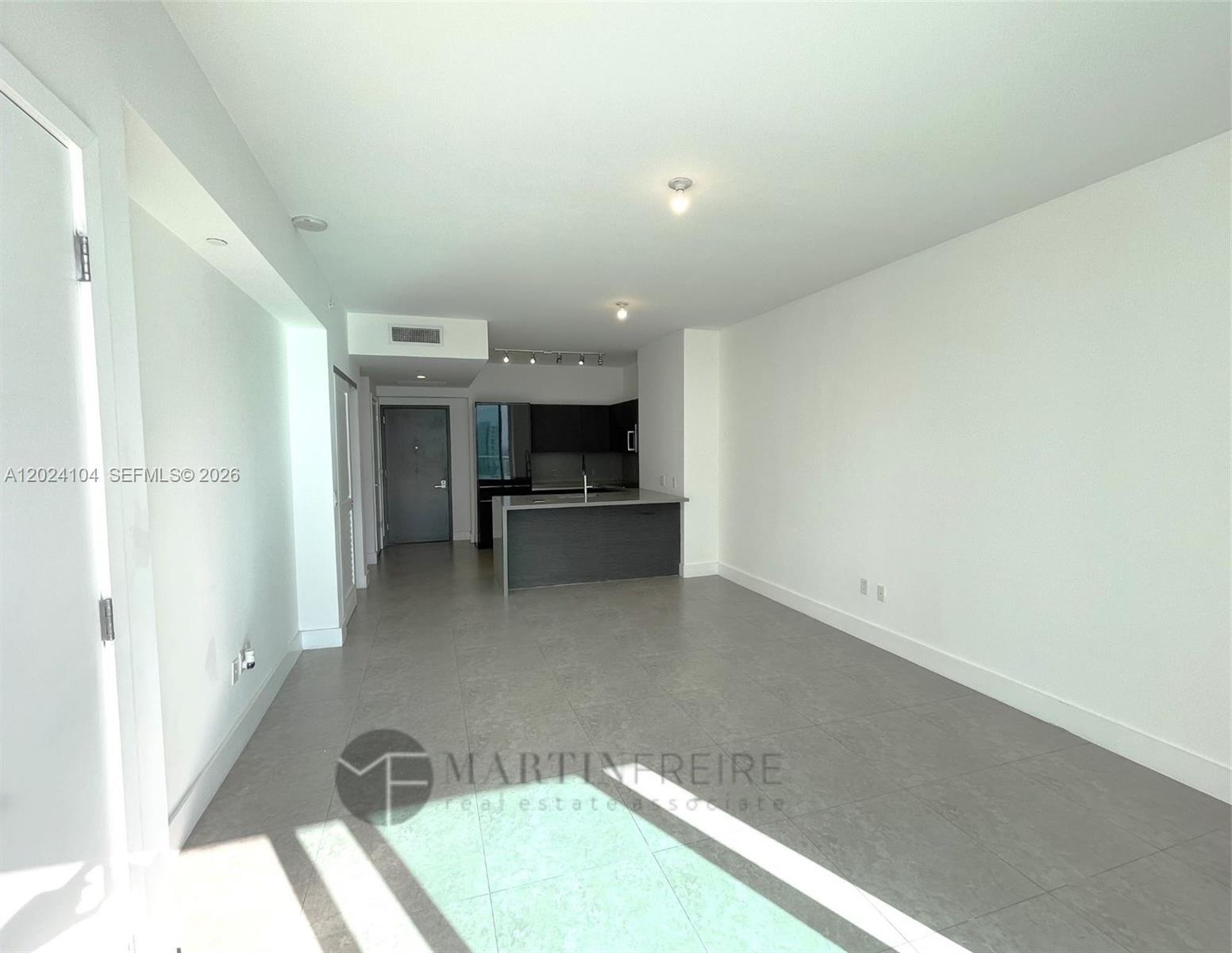 This open-concept living area features gray tile flooring and a modern kitchen with dark cabinetry — 1080 Brickell Ave # 2005, Miami FL 33131, MIAMI, FL