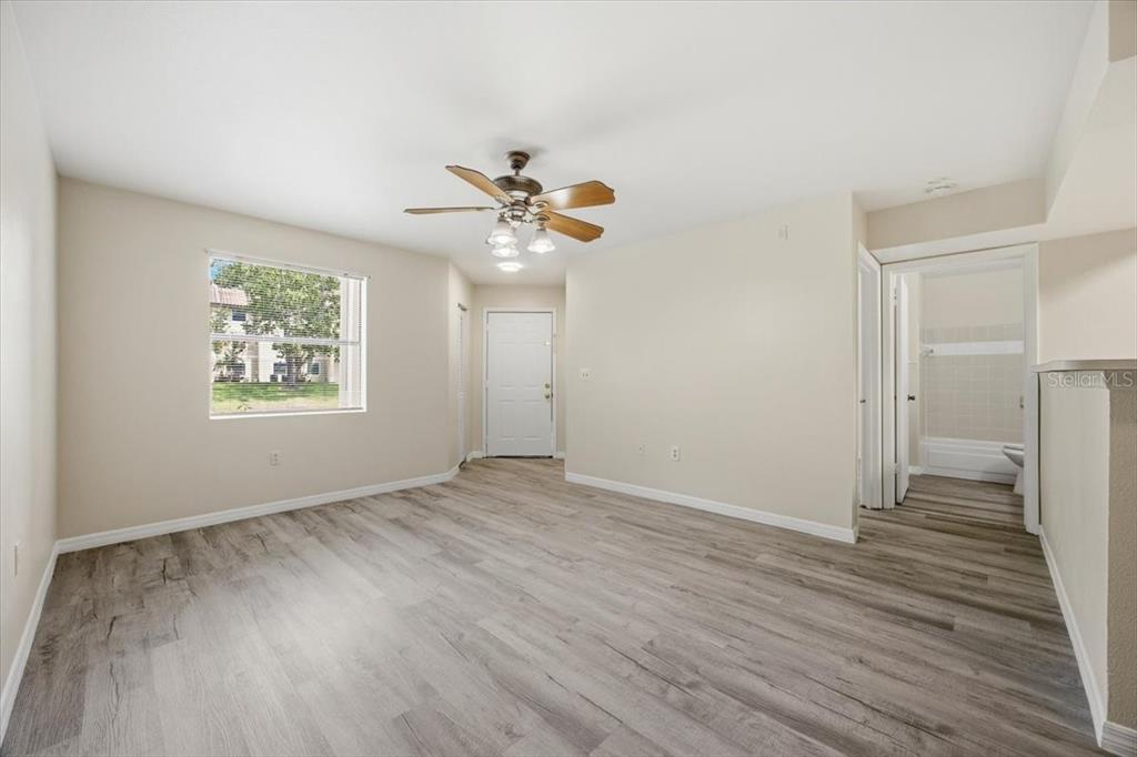 A room with light-colored walls, wood-look flooring, a ceiling fan, a window, and a bathroom — 3004 PARKWAY BOULEVARD UNIT 106, KISSIMMEE, FL