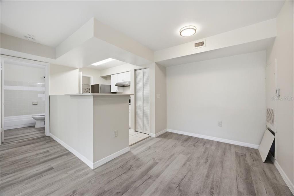 A living area with wood-look flooring, a breakfast bar, and an adjacent kitchen — 3004 PARKWAY BOULEVARD UNIT 106, KISSIMMEE, FL