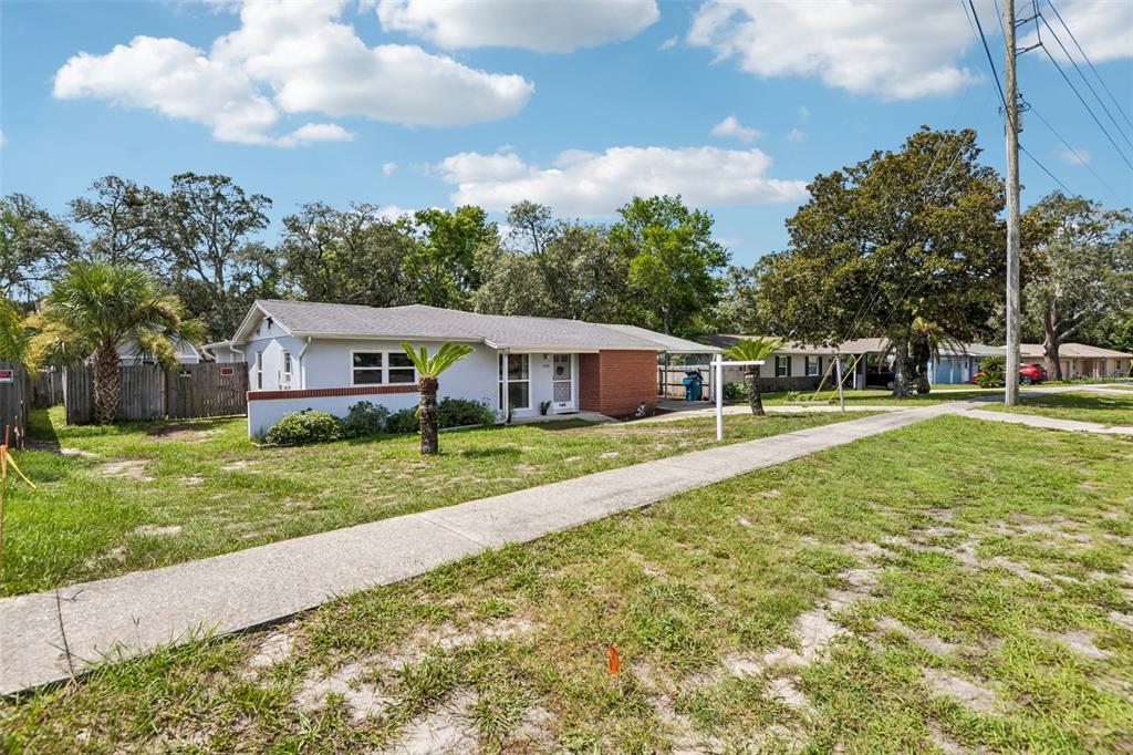 A single-story house with a brick accent wall, a front lawn, and a concrete sidewalk — 7446 PINEHURST DRIVE, SPRING HILL, FL