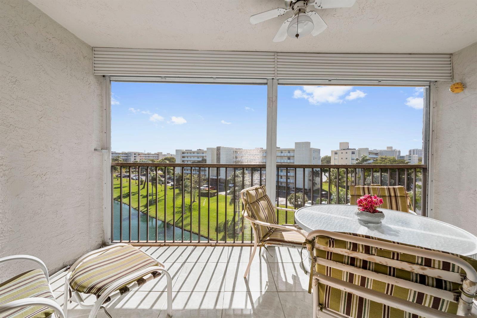 A screened-in balcony features tile flooring, a ceiling fan, and outdoor furniture overlooking a canal — 170 SE 5th Avenue Apt 505, Dania Beach FL 33004, DANIA BEACH, FL