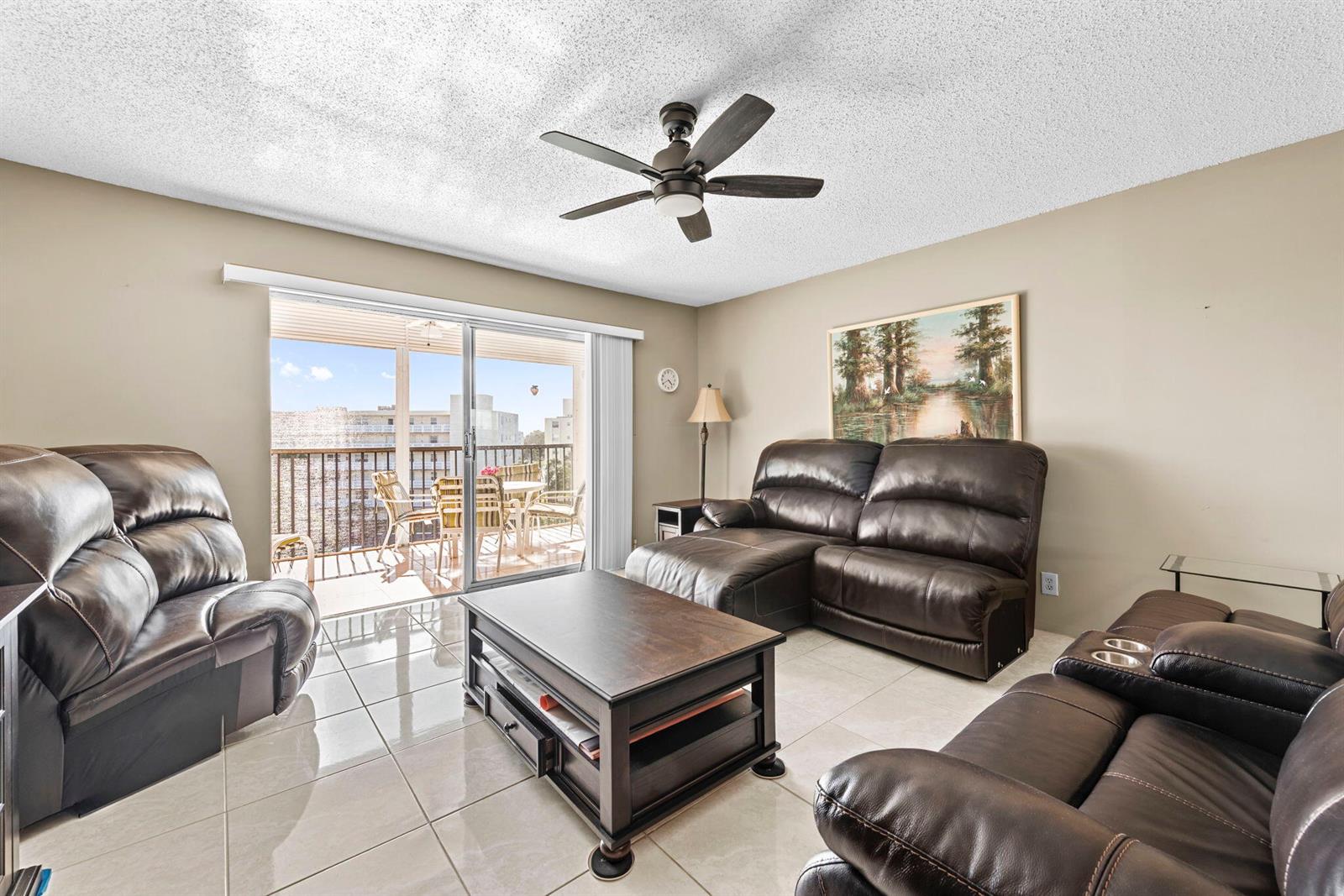 A living room features tile flooring, brown leather furniture, a coffee table, and a balcony — 170 SE 5th Avenue Apt 505, Dania Beach FL 33004, DANIA BEACH, FL