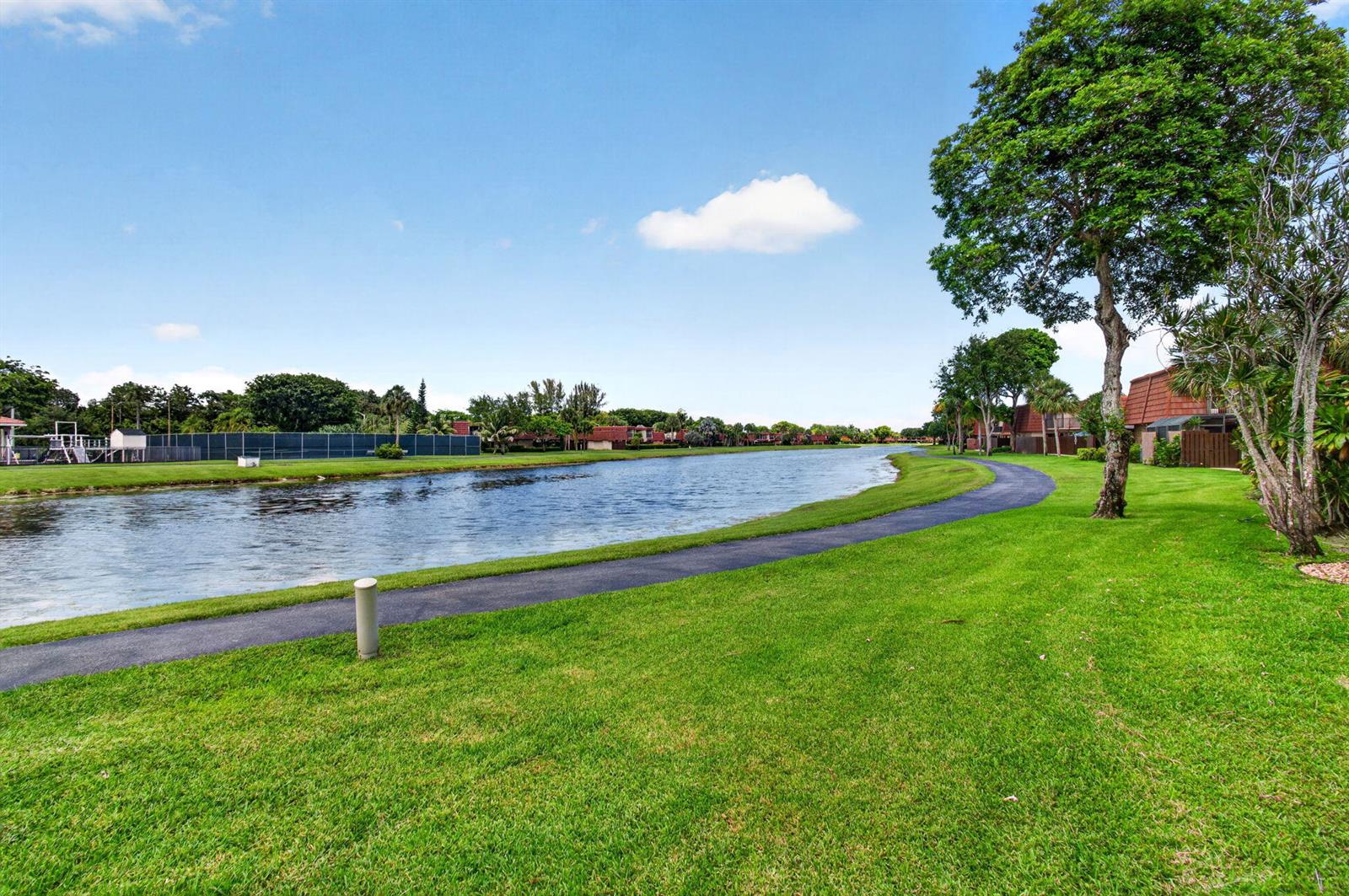 A paved path winds alongside a lake bordered by green grass and mature trees — 8377 Boca Rio Drive, Boca Raton FL 33433, BOCA RATON, FL