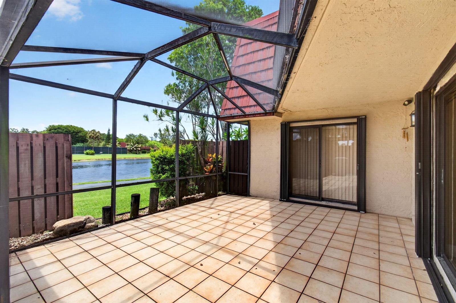 A screened-in patio with tiled flooring overlooks a lake and green space — 8377 Boca Rio Drive, Boca Raton FL 33433, BOCA RATON, FL