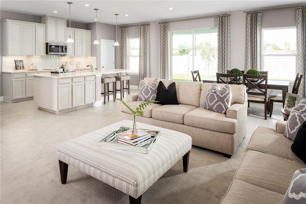 An open-concept living room and kitchen featuring light cabinetry, a large island, and neutral furniture — 423 HAMMOCK OAKS BOULEVARD, LADY LAKE, FL