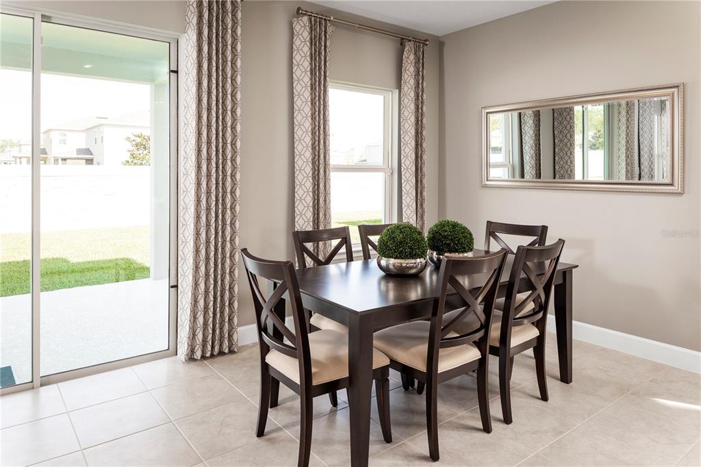 A dining area features a dark wood table with four chairs, tile flooring, and curtains — 423 HAMMOCK OAKS BOULEVARD, LADY LAKE, FL