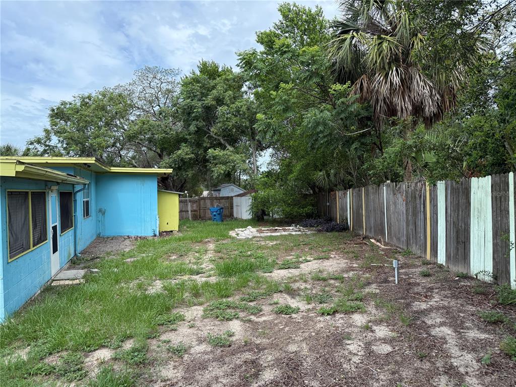 A backyard with a blue house, a wooden fence, and a small storage shed — 6093 ASHLAND DRIVE, SPRING HILL, FL