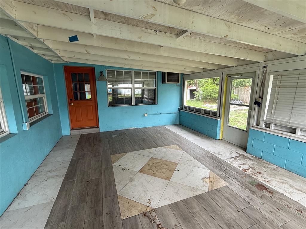 A covered patio with blue walls, wood-look tile flooring, and a central decorative tile inlay — 6093 ASHLAND DRIVE, SPRING HILL, FL