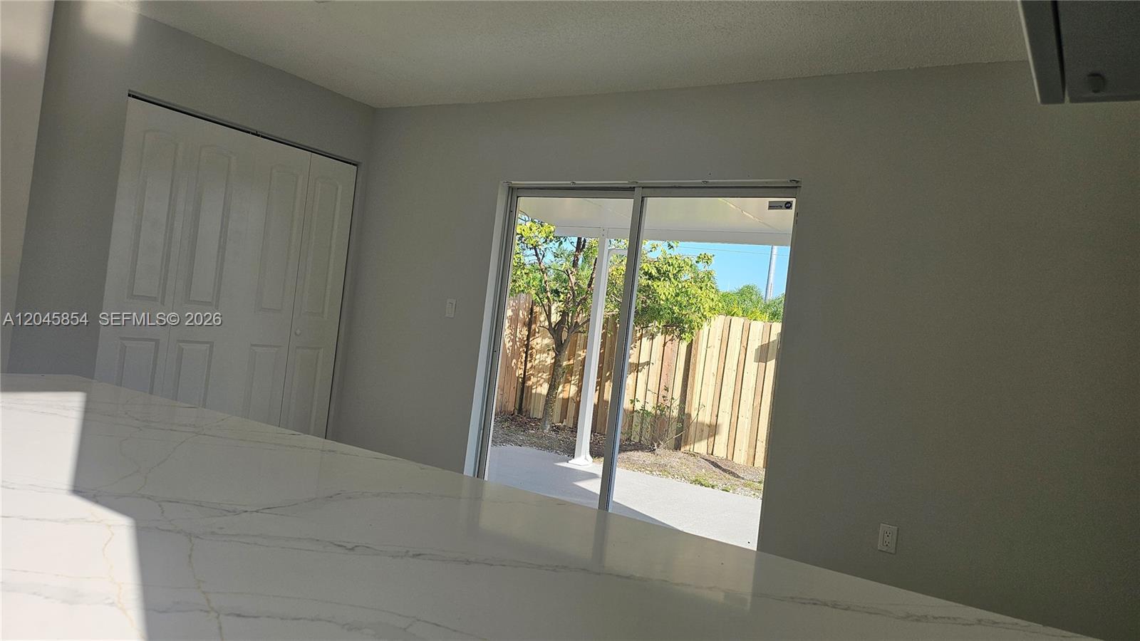 A kitchen with a white marble countertop overlooks a patio through a sliding glass door — 16125 SW 137th Ct, Miami FL 33177, MIAMI, FL