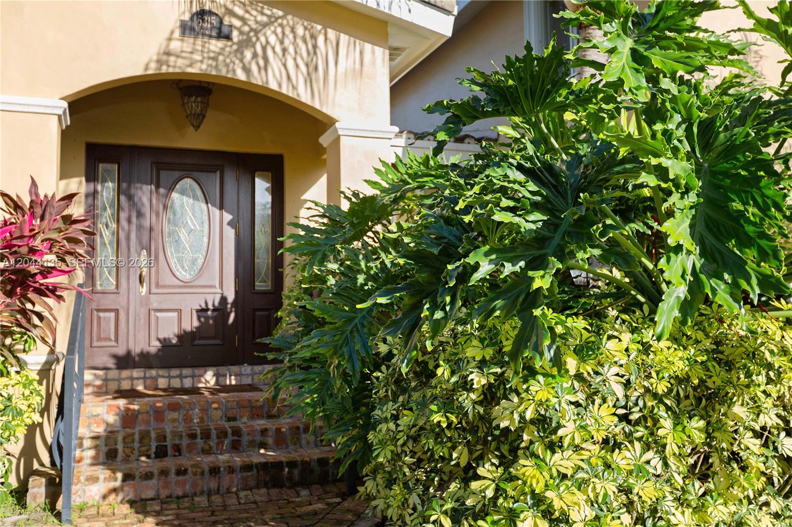 The front entrance features a dark wood door with glass panels and brick steps — 6315 Maynada St, Coral Gables FL 33146, CORAL GABLES, FL