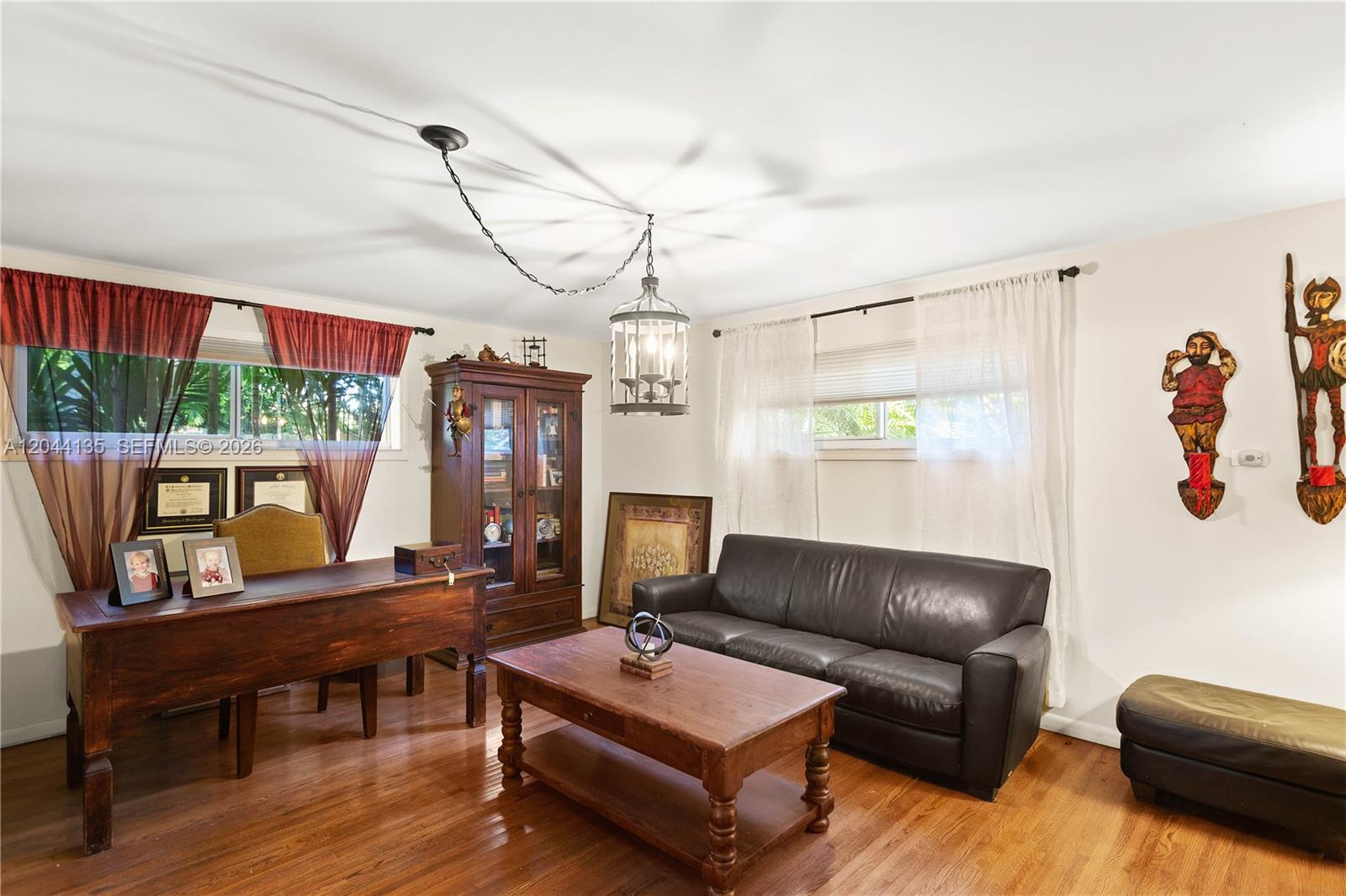 A home office features a wooden desk, a dark leather sofa, and a central chandelier — 6315 Maynada St, Coral Gables FL 33146, CORAL GABLES, FL