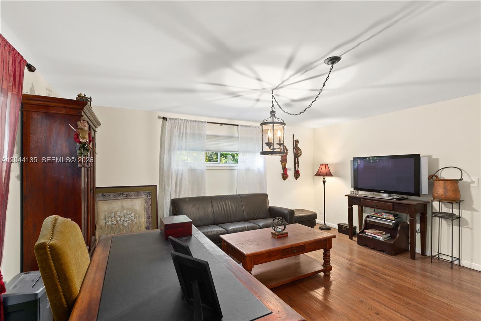 This living room features wood flooring, a leather sofa, a coffee table, and a desk — 6315 Maynada St, Coral Gables FL 33146, CORAL GABLES, FL