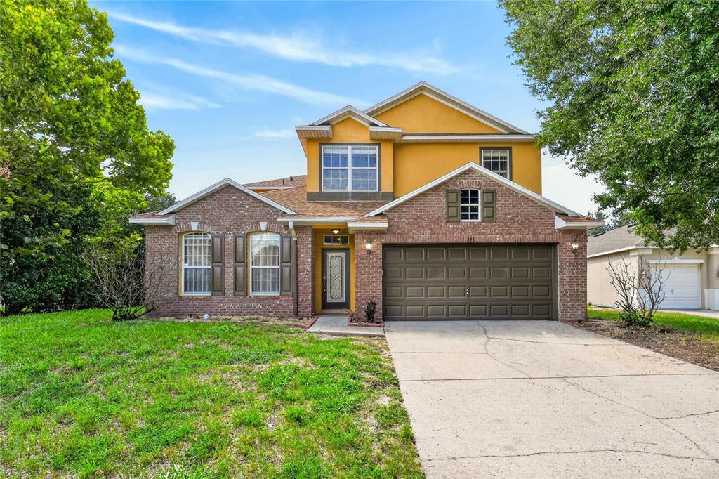 A two-story house with a brick facade, yellow upper level, and a two-car garage — 223 LARGOVISTA DR., OAKLAND, FL