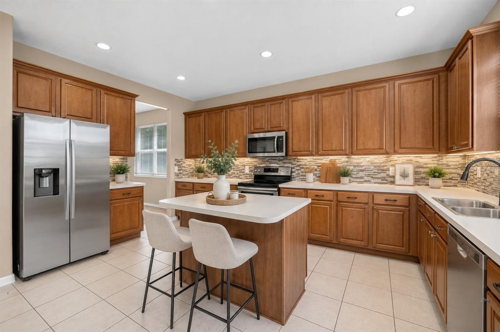 A kitchen with wood cabinets, stainless steel appliances, a center island, and tiled flooring — 223 LARGOVISTA DR., OAKLAND, FL