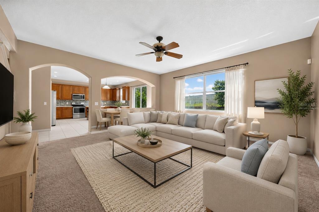 A living room with beige carpet, a sectional sofa, a coffee table, and an arched entryway — 223 LARGOVISTA DR., OAKLAND, FL