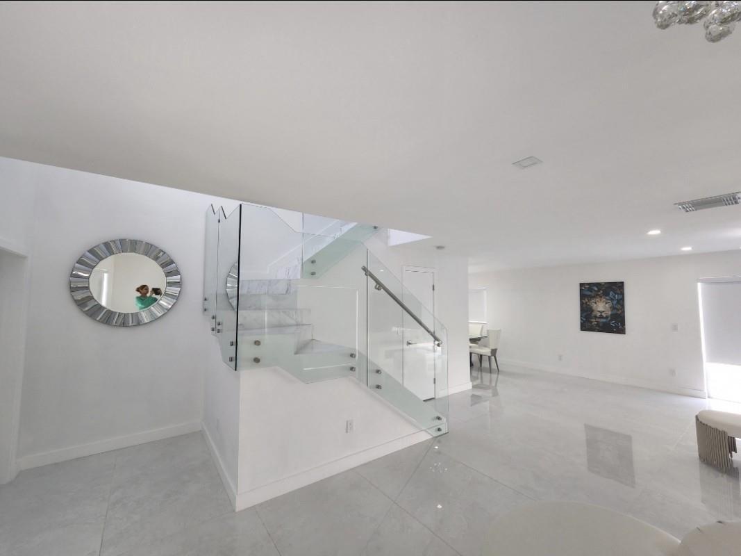 A modern living area features white tile floors, a glass-railed staircase, and a circular mirror — 9706 NW 51st Terrace, Doral FL 33178, DORAL, FL