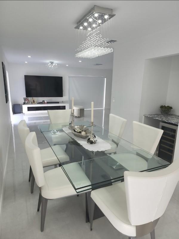 A modern dining room features a glass table, white chairs, and a crystal chandelier — 9706 NW 51st Terrace, Doral FL 33178, DORAL, FL