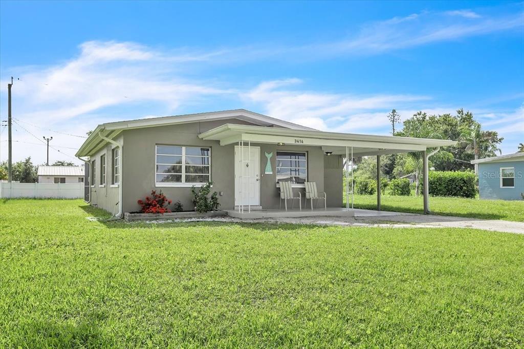 A single-story gray house with a front porch and carport sits on a grassy lot — 3414 ASH STREET, PUNTA GORDA, FL