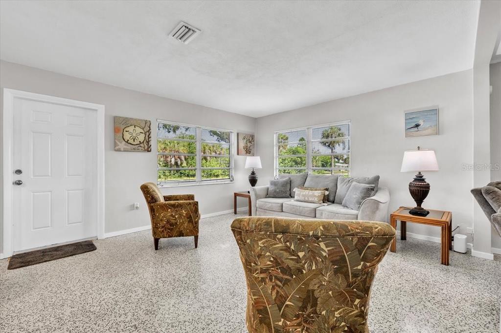 A living room features a grey sofa, two patterned armchairs, and speckled flooring — 3414 ASH STREET, PUNTA GORDA, FL
