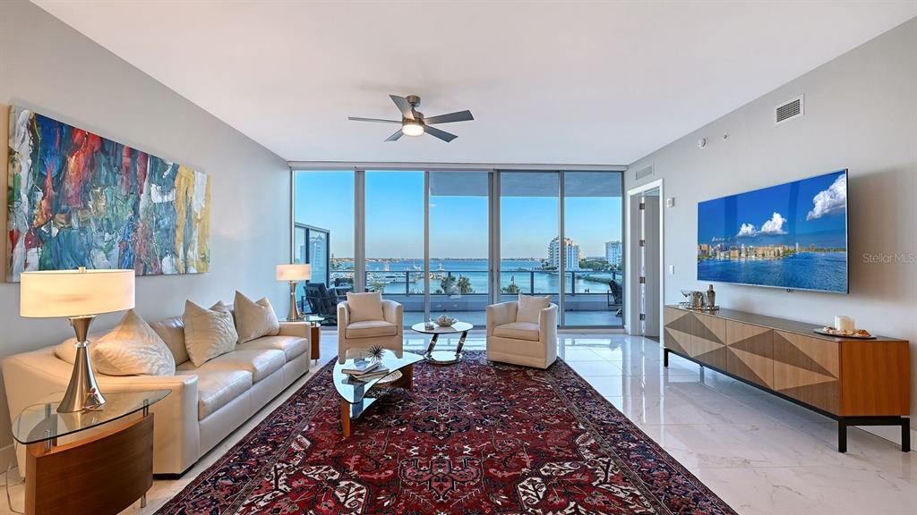A living room features a large red area rug, white sofa, and floor-to-ceiling windows — 1155 N GULFSTREAM AVENUE UNIT 401, SARASOTA, FL