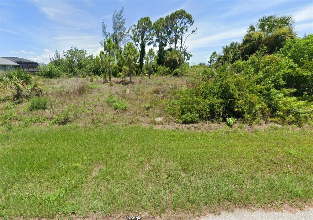 A vacant, grassy lot with scattered trees and shrubs under a bright blue sky — 15664 ALDAMA CIRCLE, PORT CHARLOTTE, FL