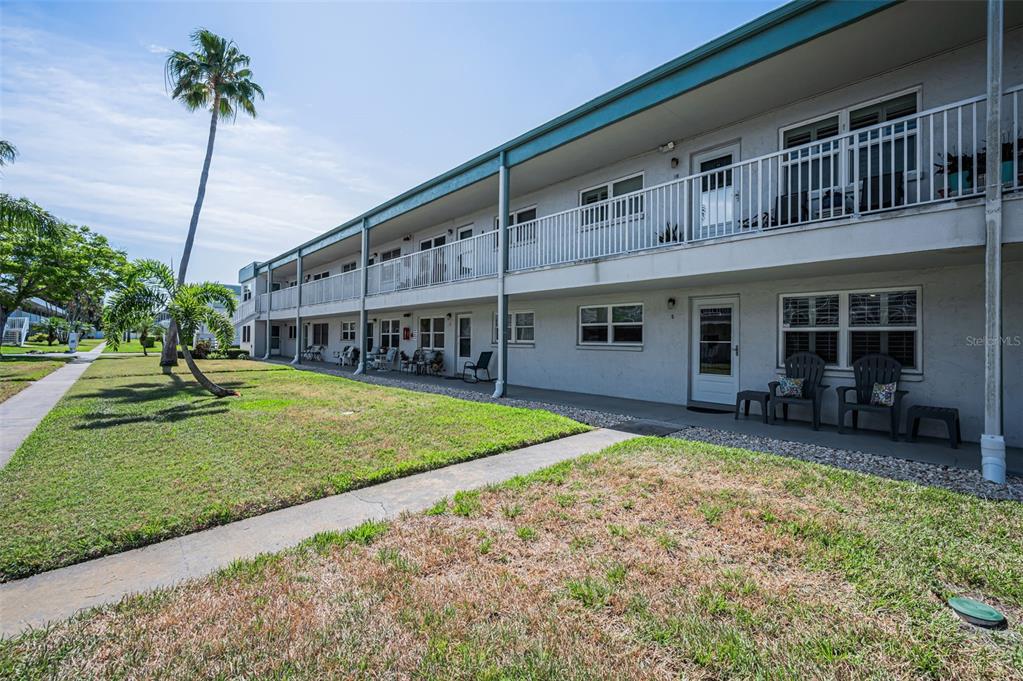 A two-story apartment building with a white exterior, balcony, and ground-level patio area — 5216 81ST STREET N UNIT 5, ST PETERSBURG, FL