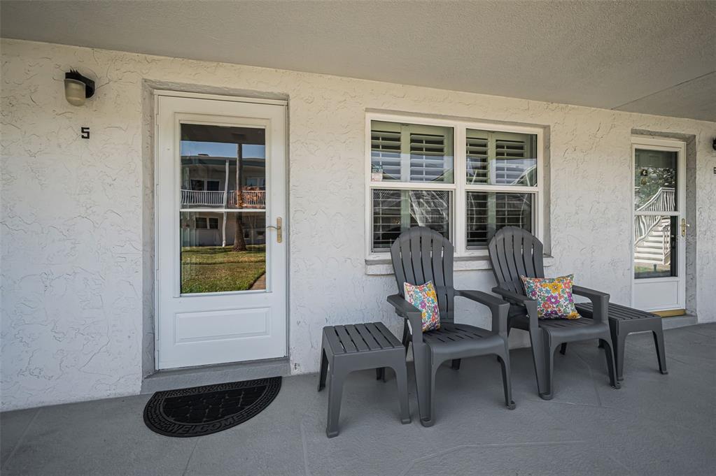A patio features two gray chairs, two small side tables, and a white entry door — 5216 81ST STREET N UNIT 5, ST PETERSBURG, FL