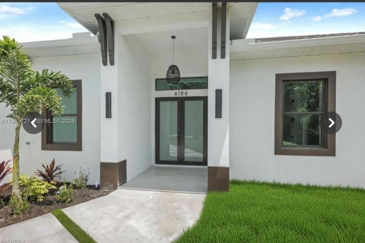The front entrance of a modern white house features a glass double door and columns — 6186 N Everglades blvd, Naples FL 34120, NAPLES, FL