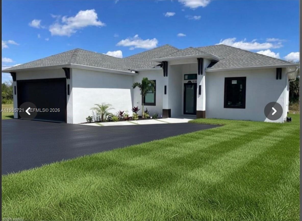 A single-story white house with a black garage door, dark window frames, and a lawn — 6186 N Everglades blvd, Naples FL 34120, NAPLES, FL