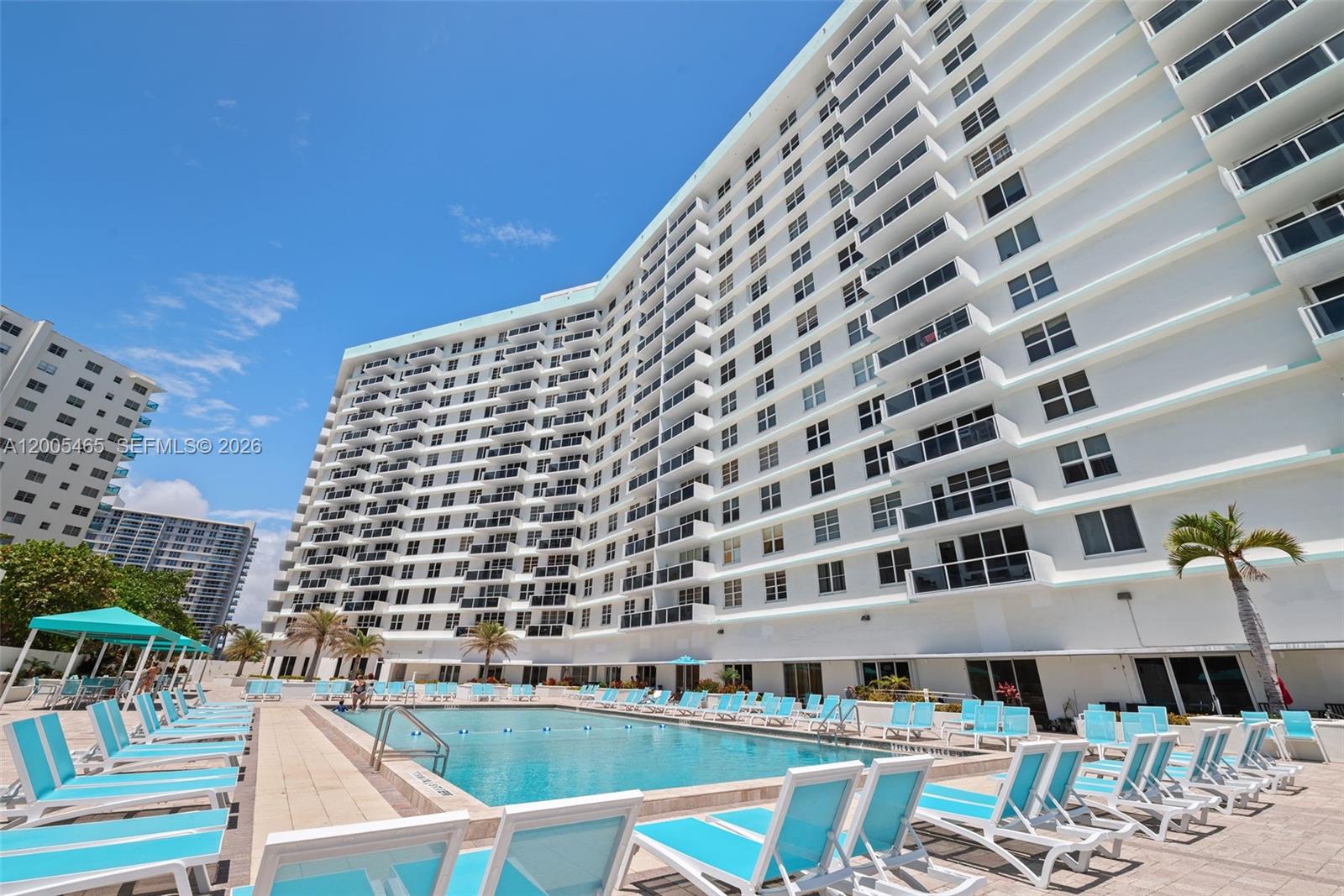 A large white apartment building overlooks a swimming pool surrounded by rows of lounge chairs — 3725 S Ocean Dr # 1212, Hollywood FL 33019, HOLLYWOOD, FL