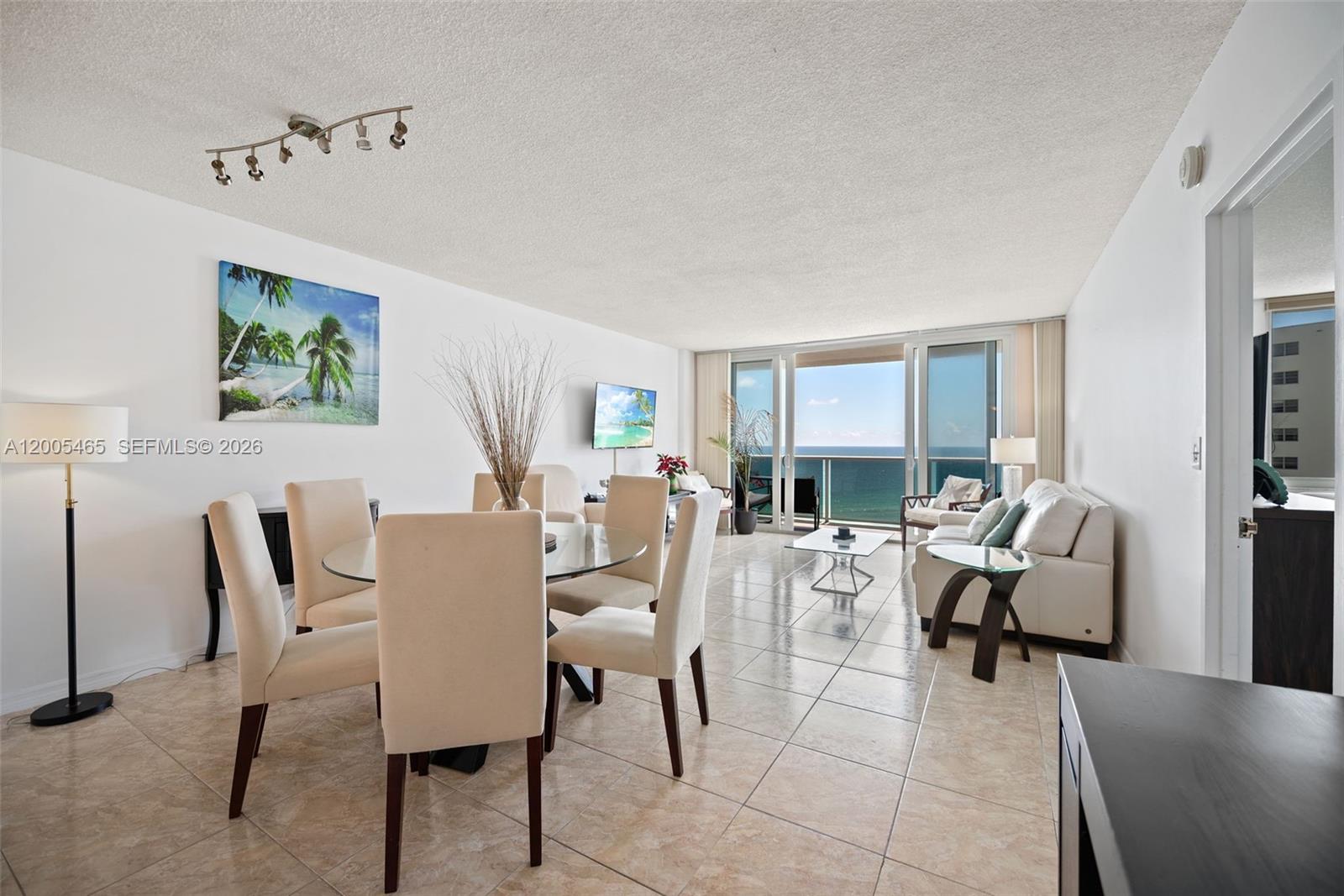 An open-concept living and dining area features tile floors, white walls, and ocean views — 3725 S Ocean Dr # 1212, Hollywood FL 33019, HOLLYWOOD, FL