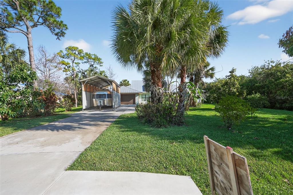 A driveway leads to a metal carport housing a trailer in front of a house — 8535 SE MAY TERRACE, HOBE SOUND, FL