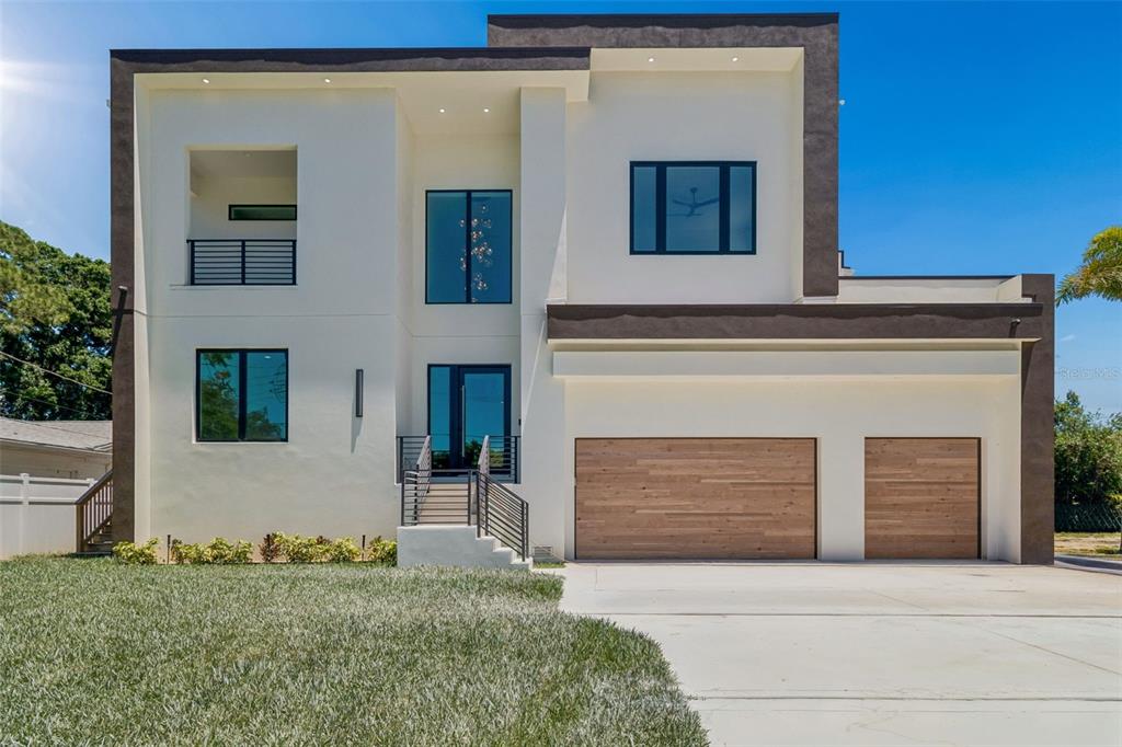 A modern two-story house with a white stucco exterior, dark trim, and a three-car garage — 206 S TREASURE DRIVE, TAMPA, FL