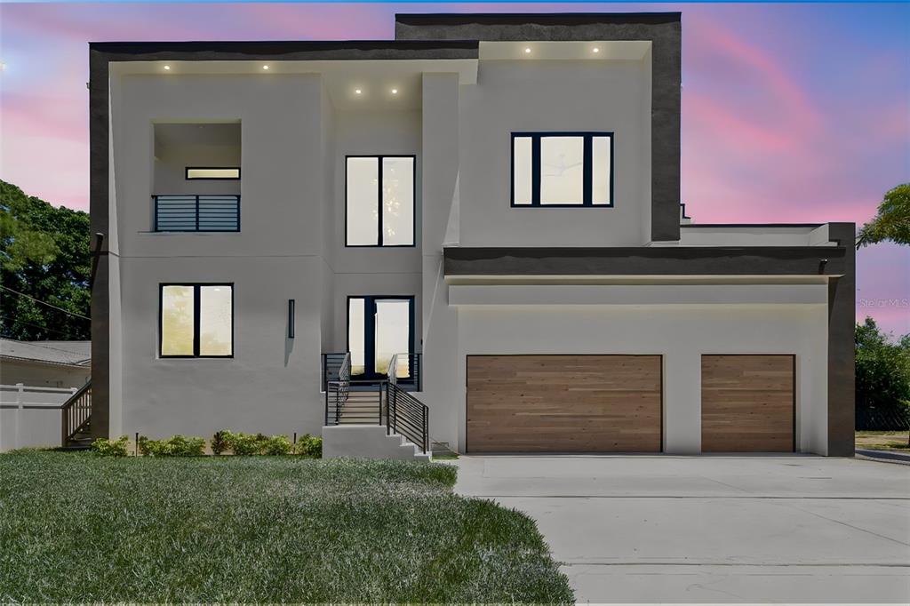 A modern two-story house with a white stucco facade, dark trim, and a three-car garage — 206 S TREASURE DRIVE, TAMPA, FL