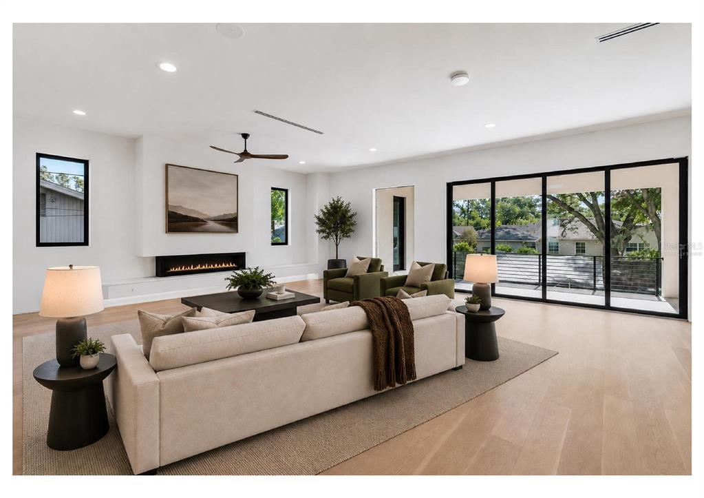 A modern living room features a fireplace, neutral furniture, and large sliding glass doors — 206 S TREASURE DRIVE, TAMPA, FL