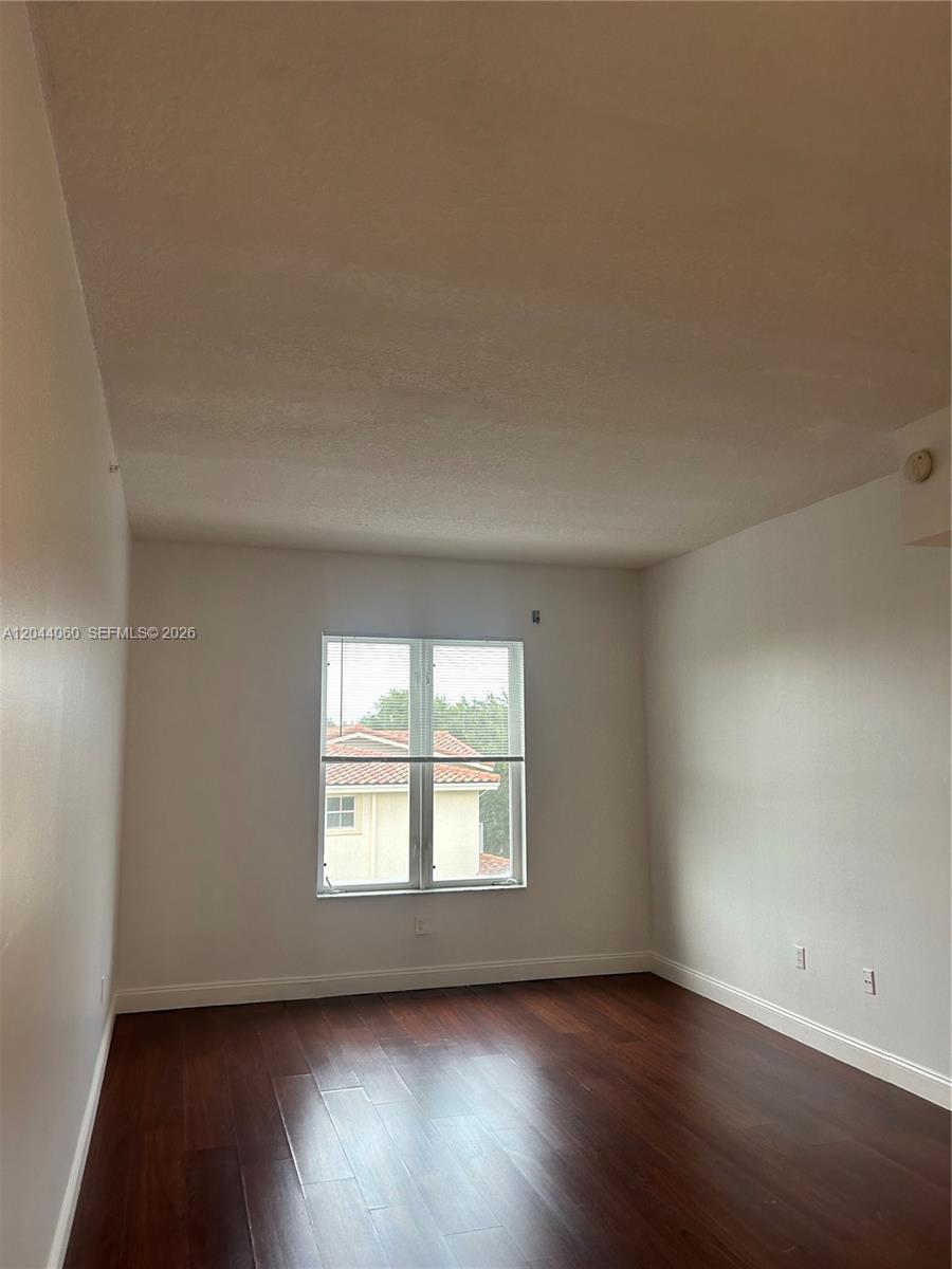 An empty bedroom features dark wood flooring, white walls, and a single window — 1155 Main St # 301, Jupiter FL 33458, JUPITER, FL