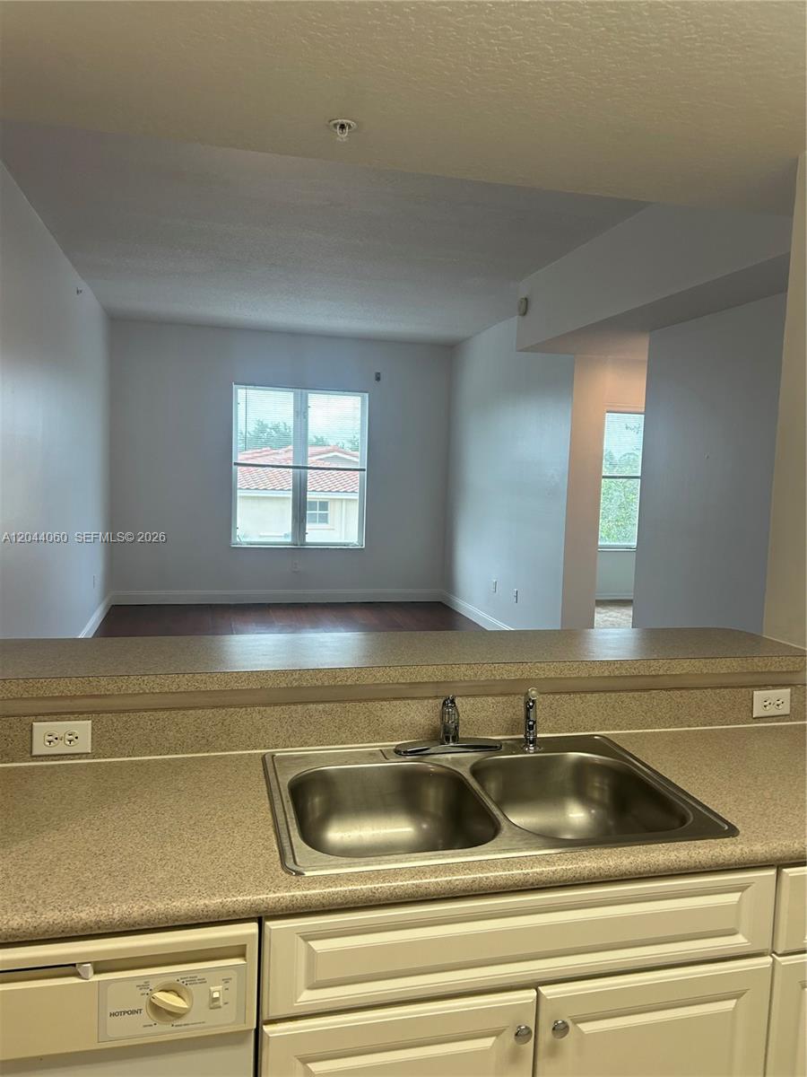 A kitchen sink and countertop overlook a living area with wood flooring and windows — 1155 Main St # 301, Jupiter FL 33458, JUPITER, FL