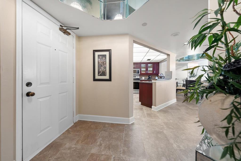 An entryway with tile flooring leads to a kitchen with dark wood cabinets — 1310 GULF BOULEVARD UNIT 10B, CLEARWATER BEACH, FL