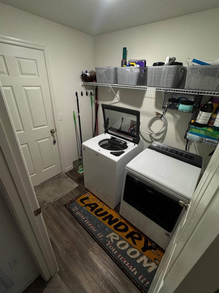A laundry room featuring a top-load washer, dryer, wire shelving, and wood-look flooring — PORT ST. LUCIE, FL
