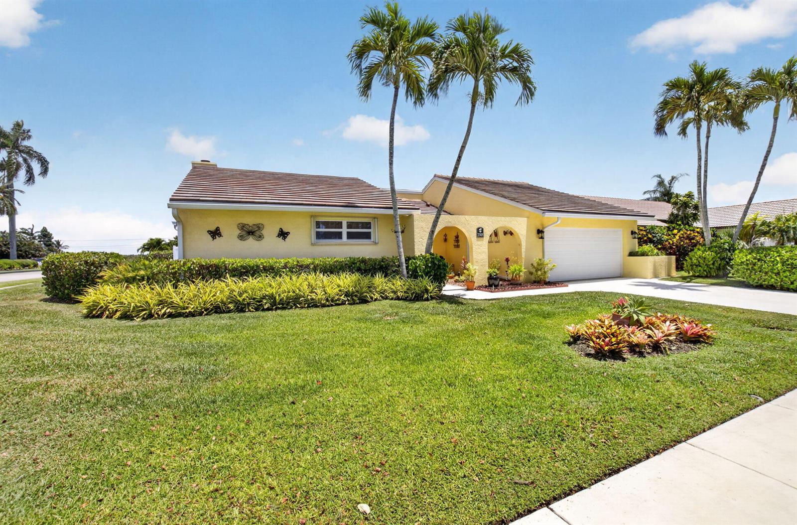 A yellow single-story house with a two-car garage and palm trees in the front yard — 2305 SW 23rd Cranbrook Drive, Boynton Beach FL 33436, BOYNTON BEACH, FL
