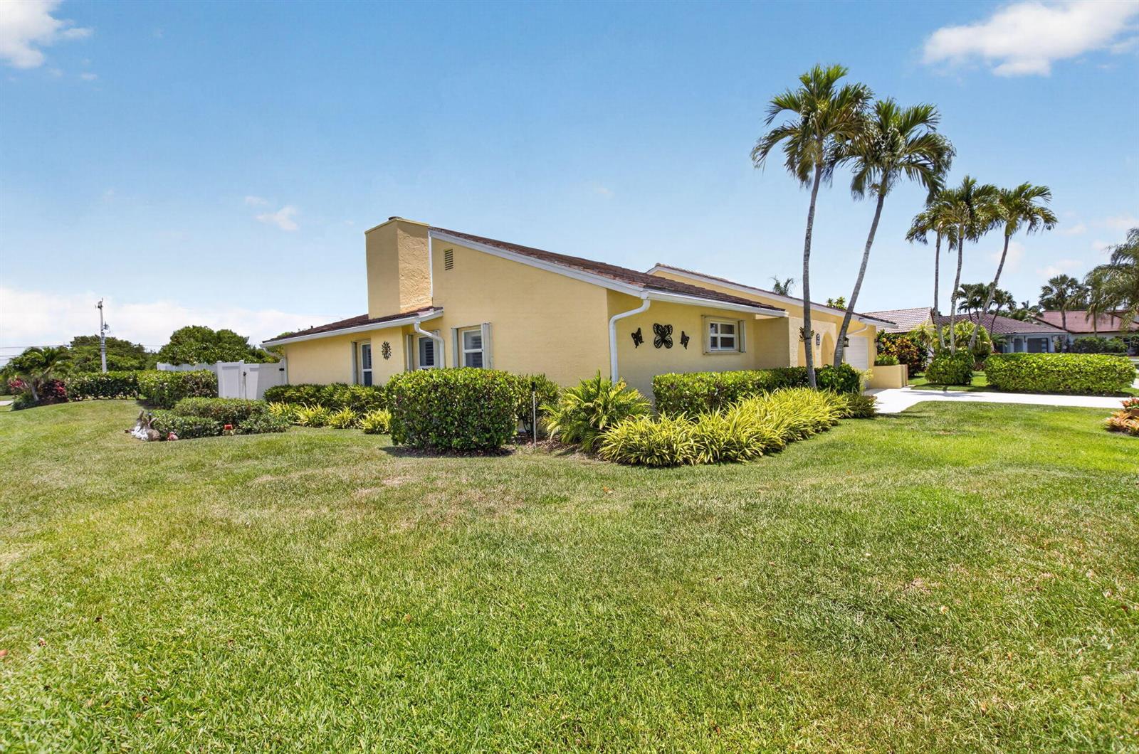 A yellow single-story house with a chimney and palm trees sits on a grassy lawn — 2305 SW 23rd Cranbrook Drive, Boynton Beach FL 33436, BOYNTON BEACH, FL