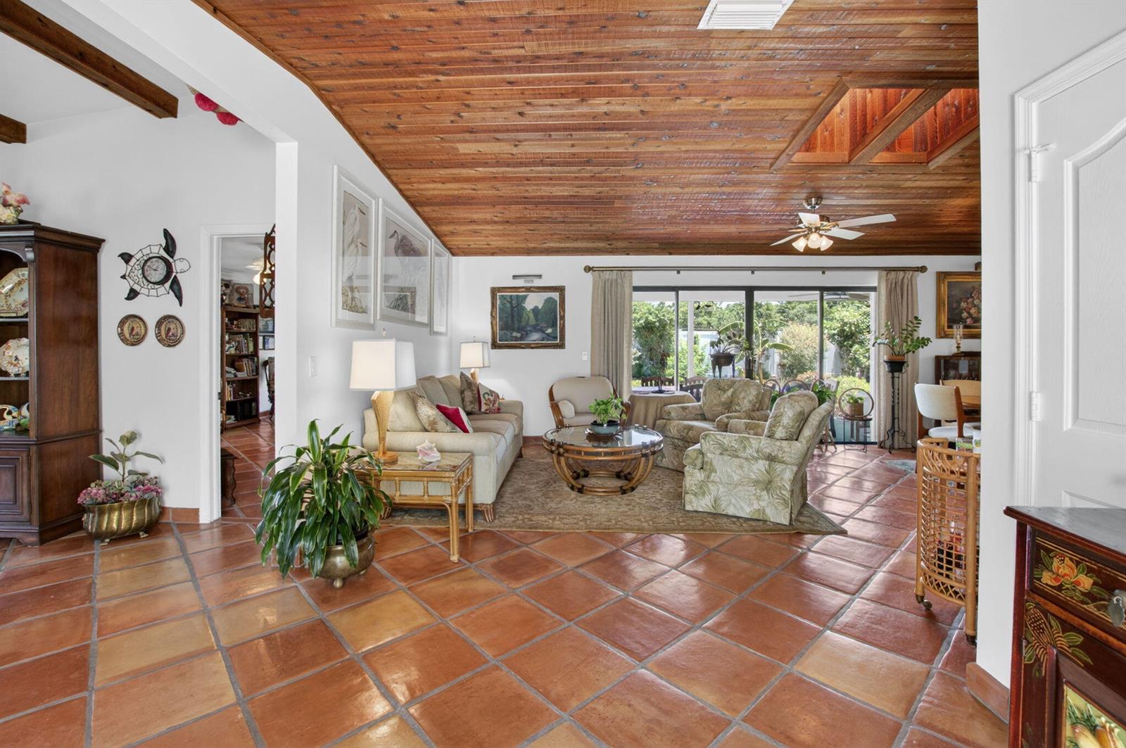 A living room features terracotta tile floors, a wood-paneled vaulted ceiling, and sliding glass doors — 2305 SW 23rd Cranbrook Drive, Boynton Beach FL 33436, BOYNTON BEACH, FL