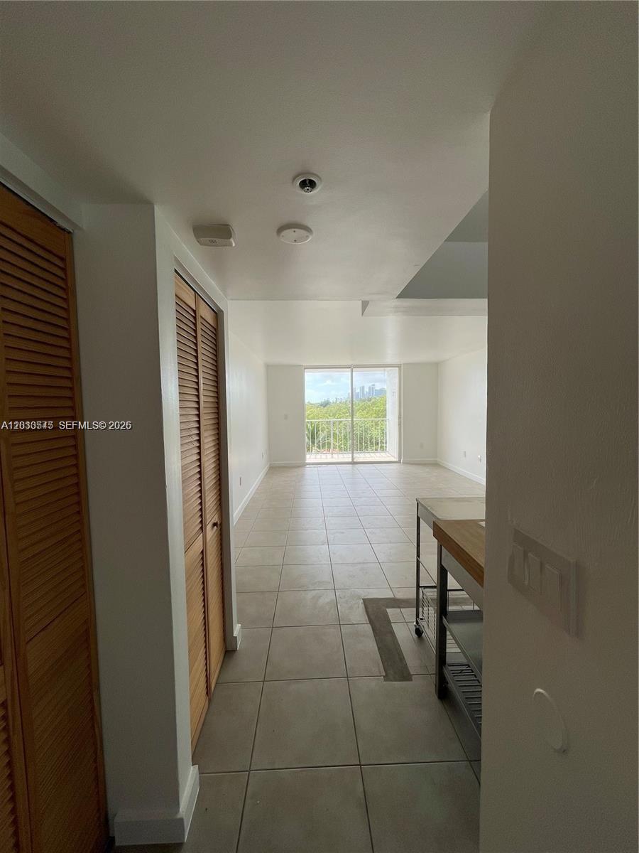 A tiled hallway leads to a living area with a balcony overlooking trees and buildings — 700 NE 63rd St # D606, Miami FL 33138, MIAMI, FL