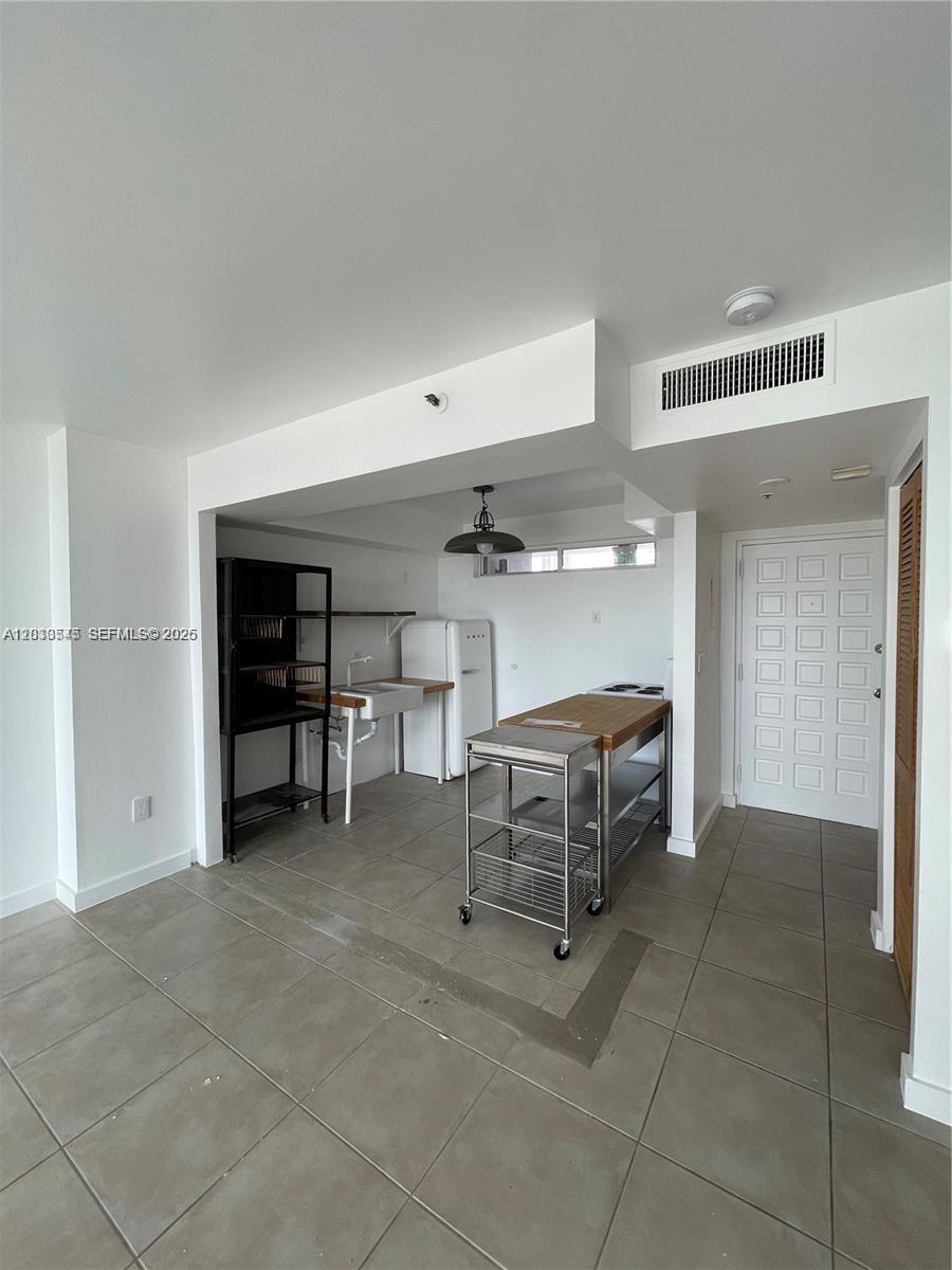 A small kitchen area features tiled floors, a stainless steel island, and a white refrigerator — 700 NE 63rd St # D606, Miami FL 33138, MIAMI, FL